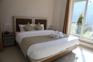 una camera da letto con un letto grande con una grande finestra di Hotel yog tapovan MOUNTAIN VIEW ROOM a Rishikesh