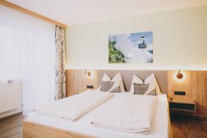 a bedroom with a white bed and a window at Pension Monika, Summercard included in Kaprun