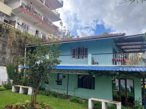 a blue house with a balcony and a building at Sparrow valley in Coonoor