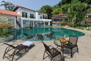 a swimming pool with chairs and a table in front of a house at Angra Boutique Hotel in Angra dos Reis