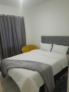 a bedroom with a large bed with a gray blanket on it at The Nexus Suites in Gaborone