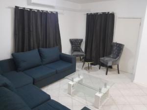 een woonkamer met een blauwe bank en stoelen bij The Nexus Suites in Gaborone