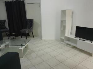 a living room with a tv and a tiled floor at The Nexus Suites in Gaborone