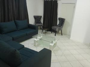 een woonkamer met een blauwe bank en stoelen bij The Nexus Suites in Gaborone