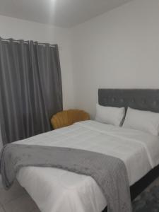 een slaapkamer met een groot bed met witte lakens en kussens bij The Nexus Suites in Gaborone