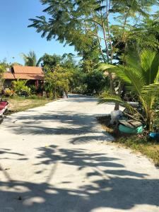 een weg met bomen en een huis in de verte bij Green moon Home stay 51 in Buriram