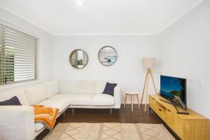 a living room with a white couch and a tv at Byron Lakeside Holiday Apartments in Byron Bay