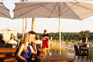 a group of people sitting at a table under an umbrella at Stay2Munich Hotel & Serviced Apartments in Brunnthal