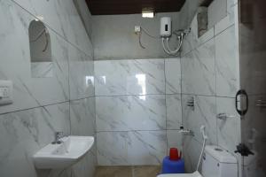 a white bathroom with a sink and a toilet at Coorg Backwaters in Suntikoppa