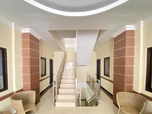 a hallway with stairs and chairs in a building at Lily Guest House Syariah RedPartner in Bunul