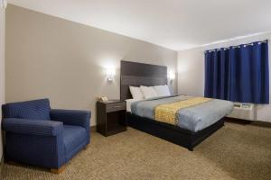 a hotel room with a bed and a chair at Rodeway Inn Branson, Brick House in Branson +32 photos