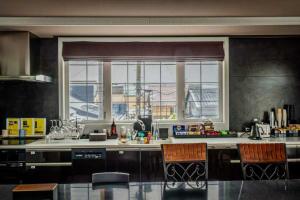 美瑛町Biei Terrace 2F 専用玄関 127平米 85型スマートTV -駅前通り&景観条例地区-的一个带两把椅子和大窗户的厨房