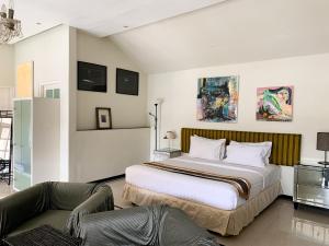 a bedroom with a large bed and a couch at Casa Artista By Kresna Hospitality in Seminyak