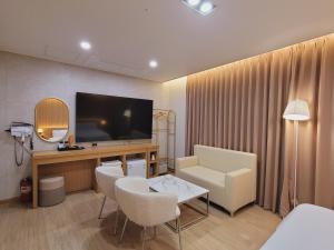a living room with a television and a couch and chairs at 호텔휴 