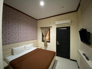 a bedroom with a bed and a black door at Lily Guest House Syariah RedPartner in Bunul +30 photos