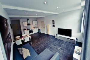 sala de estar con sofá azul y TV en Apart'Hotel Liège City Centre en Lieja