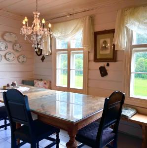 a dining room table with chairs and a chandelier at Charming Guesthouse farm in Hølera