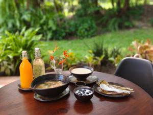 a table with a bowl of soup and bottles of juice at บ้านสวนปรีดา-Preda Garden Home in Sam Phran