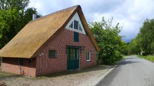 een klein rood bakstenen gebouw met een rieten dak bij Haus Käthe am Deich in Balje