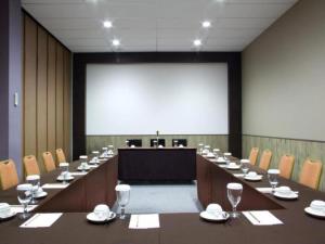 une salle de conférence avec une longue table et un grand écran dans l'établissement Plan B Hotel, à Kampungdurian