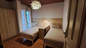 a small bedroom with two beds and a chandelier at Da Nonna Isa - Ampio appartamento tra Bormio e Bernina Express in Grosotto