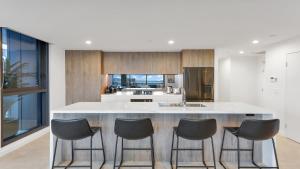 een keuken met een groot eiland met vier stoelen bij Revive At Archibald Accom Holidays in Gosford