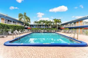 a swimming pool with chairs and a building at Rodeway Inn & Suites Fort Lauderdale Airport & Cruise Port in Fort Lauderdale