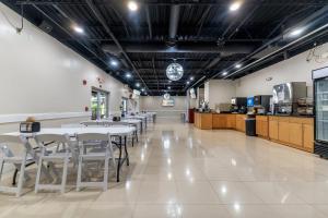 a restaurant with white tables and chairs and a kitchen at Rodeway Inn & Suites Fort Lauderdale Airport & Cruise Port in Fort Lauderdale