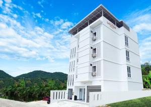 un edificio bianco con montagne sullo sfondo di Laksika Place Khao Rang a Phuket