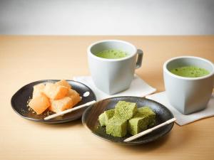 zwei Tassen grüne Suppe und zwei Teller Essen in der Unterkunft Comfort Hotel ERA Kyoto Toji in Kyoto