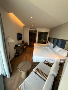 a hotel room with two beds and a table at APEC Mandala Mũi Né VIP in Mui Ne