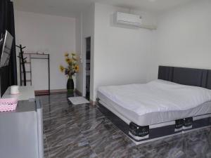 een slaapkamer met een bed en een vaas met bloemen bij Saint Jira Hotel in Chum Phae