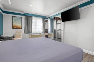 una camera da letto con un grande letto bianco in una stanza di Rodeway Inn Commerce - Los Angeles a Commerce