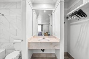 un bagno con lavandino, WC e specchio di Rodeway Inn Commerce - Los Angeles a Commerce Altre 42 foto