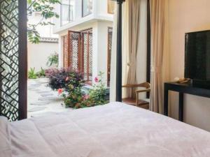 een slaapkamer met een bed en een balkon met bloemen bij Dali Four Seasons Hostel in Dali (oude stad)