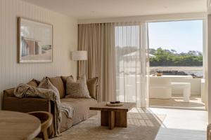 a living room with a couch and a view of the ocean at Nomaya Waterfront Getaway in Currarong