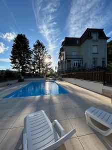 een zwembad met 2 ligstoelen naast een huis bij Camping du Château in Granges-sur-Vologne