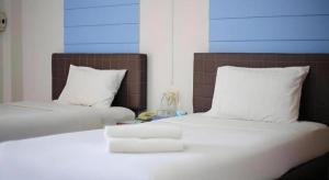 two beds with white sheets and pillows in a room at Kumkaew Udon in Udon Thani