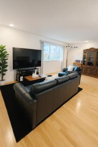 a living room with a leather couch and a flat screen tv at Great Northern Escapes - The Managers House in Yellowknife