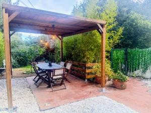 een houten paviljoen met een tafel en stoelen op een patio bij La vinya in Sant Feliu de Guixols