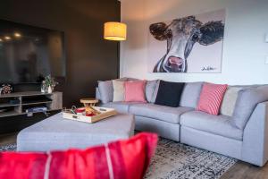 een woonkamer met een bank en een foto van een koe bij 211 - Bright Condo - Pool and Cozy Atmosphere in Baie-Saint-Paul