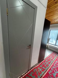 a large glass door in a room with a red rug at Жайсан in Karakol
