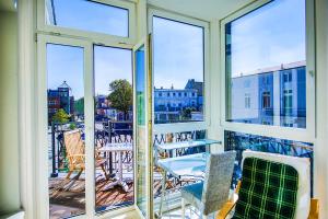 einen Balkon mit Fenstern sowie einem Tisch und Stühlen in der Unterkunft Eicher Ferienwohnungen Warnemünde in Warnemünde