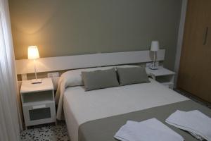 ボロニアにあるApartamentos Bolonia Paraisoのベッド1台と2泊用のスタンドが備わるホテルルームです。