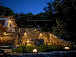 a stone wall with lights in a yard at night at Elpida's Retreat, Pelion in Tsagarada