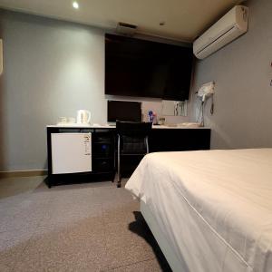 a hotel room with a bed and a desk with a tv at 스카이모텔 in Seoul