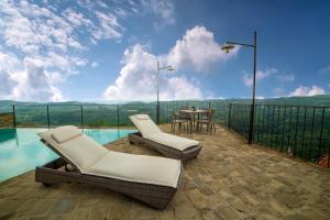patio z 2 krzesłami i stołem oraz wodą w obiekcie Dimora Storico Romantica Il Sole E La Luna w mieście Cerretto Langhe
