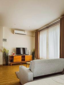 een woonkamer met een bank en een flatscreen-tv bij Villanarachaam in Cha Am