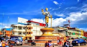 uma estátua no meio de uma cidade com pessoas em Vy Chhe Hotel em Battambang