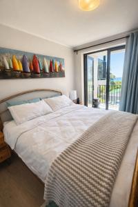 een slaapkamer met een bed en een raam met surfplanken aan de muur bij Marina Views Simon's Town in Simonʼs Town